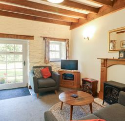 A living room with a sofa and television at Royal Oak Farm Cottage in Betws-y-Coed