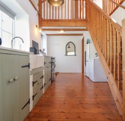 A kitchen with wooden stairs green cabinets a white refrigerator and a sink at Joe's Barn in Mullion