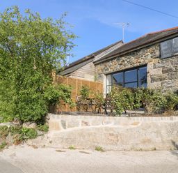 A barn with outdoor seating and plants at Joe's Barn in Mullion
