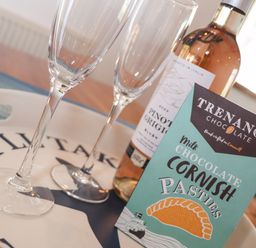 A tray with two empty wine glasses a bottle of pinot grigio and a box of milk chocolate cornish pasties at Berts Barn in Mullion
