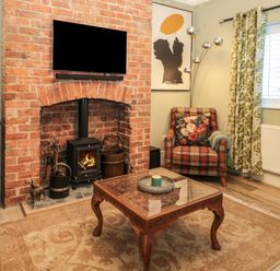 A living room with a brick fireplace armchair patterned curtains and a wooden coffee table at Sunflowers in Earsdon near Whitley Bay