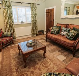 A living room with patterned curtains sofas a wooden coffee table and a large wall mirror at Sunflowers in Earsdon near Whitley Bay