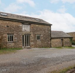A stone barn with two windows and a double glass door surrounded by gravel and grass at Brimpts Barn Dartmeet near Princetown