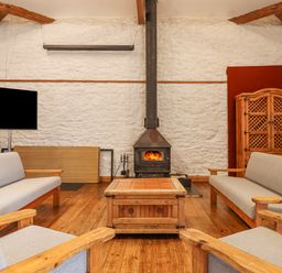 A living room with wooden furniture a wood burning stove and a television at Brimpts Barn Dartmeet near Princetown