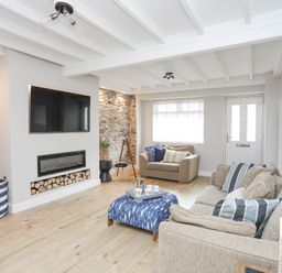 A living room with sofas a television and fireplace at Ty Bara in Cemaes Bay