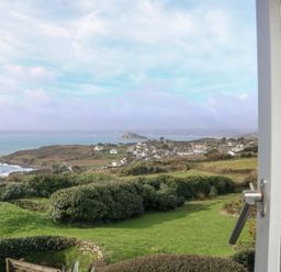 A coastal village with green fields and ocean view seen through a window at An Skyber in Perranuthnoe