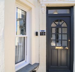 Black front door with glass panels and a window to the left on a cream painted brick house at First Light in Pakefield near Lowestoft