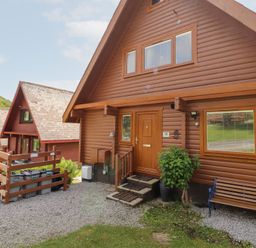 A log cabin exterior with door and windows at Thistle Dubh ('Doo') Sandyhills
