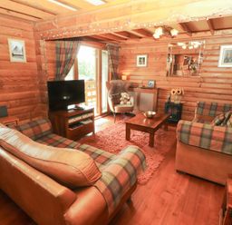 A living room with a sofa and television at Thistle Dubh ('Doo') Sandyhills