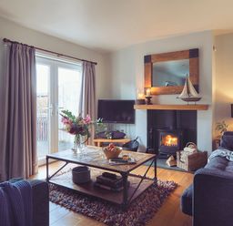 A living room with a wooden coffee table flowers and fruit bowl on the table a fireplace and sofa at Craster Reach in Craster