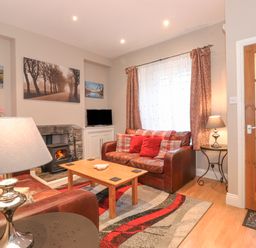 A living room with two leather sofas a wooden coffee table a fireplace and a television at Myrtle Cottage in Windermere