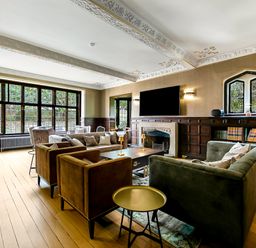 A living room with sofas armchairs a coffee table fireplace and large windows at Tudor Grange in Bournemouth