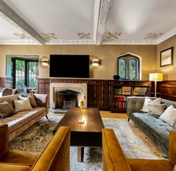 A living room with sofas armchairs a wooden coffee table a fireplace and a television at Tudor Grange in Bournemouth