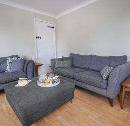A living room with two gray sofas a gray ottoman table and wooden side tables at 8 Biddlecombe Orchard in Bridport