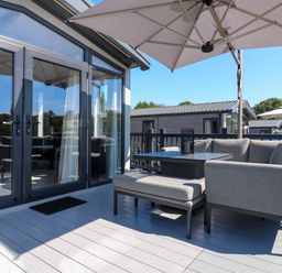An outdoor terrace with furniture and an umbrella at Lakewood Plot 2 St. Osyth