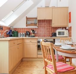 A kitchen with wooden cabinets and a dining table set with bowls and glasses at Crystals in Hatherleigh