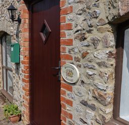 A stone cottage exterior with a wooden door a green mailbox and a plant pot at Butterton Cottage Combe Raleigh near Honiton