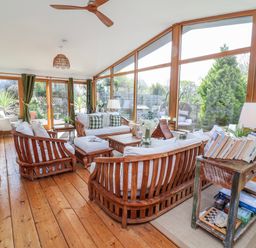 A conservatory with wooden furniture and windows at Burlodge Swimbridge near Barnstaple