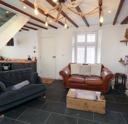 A living room with two sofas a wooden chest coffee table exposed beams and a kitchen corner at The Nook in Brixham