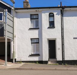 The front exterior of a white building with black door and three windows on Burton Street