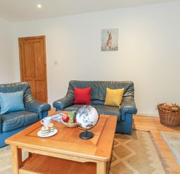A living room with two blue leather sofas and a coffee table with fruit and a globe at Coldharbour Farm Bungalow Annexe Coldharbour near Wareham