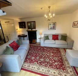 A living room with two sofas a red patterned rug and a spiral staircase at The Old Sorting Office in Hawarden
