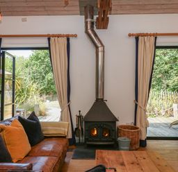 A living room with a wood stove and large windows at Burrows in Venn Ottery near Sidmouth
