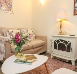 A living room with a sofa, coffee table, and lamp at Sunset Cottage in Swimbridge near Barnstaple