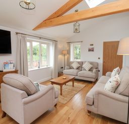 A living room with two sofas a chair coffee table wooden cabinet and large windows at Waverley Cottage in Kilnsea near Easington Hull