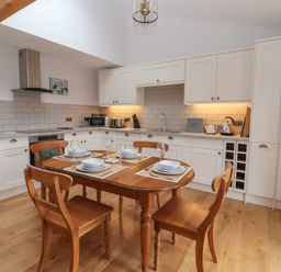 A kitchen with wooden table and chairs set with dishes and glasses at Waverley Cottage in Kilnsea near Easington Hull