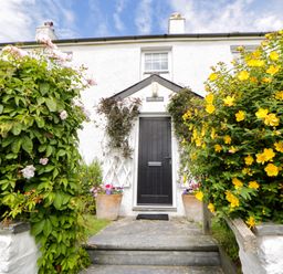 A garden with flowers and a front door at Pen y Graig Aberporth