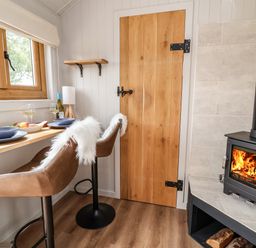 A small dining area with two chairs at a counter by a window and a wood burning stove in a corner at Cariad Mawr in Gwaenysgor near Prestatyn