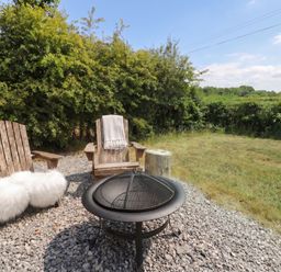 A fire pit and chairs arranged in a garden at Cariad Mawr in Gwaenysgor near Prestatyn
