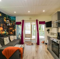 A living room with a sofa and kitchen area at Squirrels Lodge in South Molton