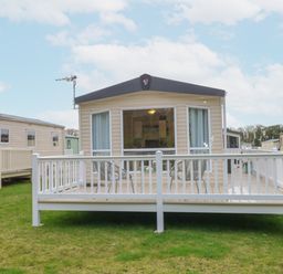 A mobile home with a white railing deck and chairs on grass at No 3 Foxburrow Hang in Belton