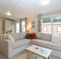 A living room with a beige sectional sofa and throw pillows a wooden coffee table with books and flowers on a table at No 3 Foxburrow Hang in Belton