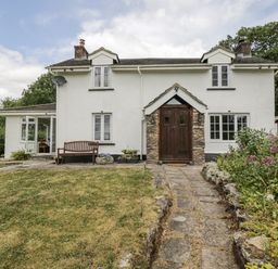A house with a wooden door and a garden at Woods Cottage in Kingcoed near Raglan