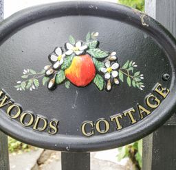 A sign with the text Woods Cottage at Woods Cottage Kingcoed near Raglan