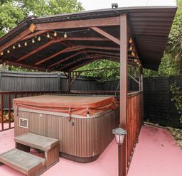 A hot tub under a wooden gazebo in an outdoor area at Woods Cottage near Raglan