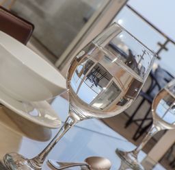 A table with two wine glasses filled with water a white bowl on a plate and a spoon at Mariners Watch in Carbis Bay