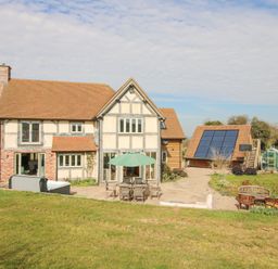 A large two storey house with a patio garden table umbrella and solar panels on a separate building at Cuckoo Pen Cottage Eastham near Tenbury Wells