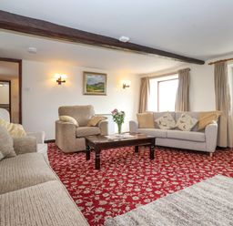 A living room with sofas a coffee table and a painting on the wall at Addyfield Farmhouse in Cartmel Fell near Bowland Bridge