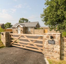 A stone cottage with a wooden gate and stone walls at Pear Tree Cottage in St Mellion near St Dominick