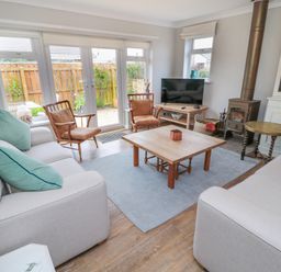 A living room with sofas chairs a coffee table a television and a fireplace at Turnstone in Beadnell