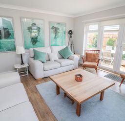 A living room with sofas chairs a wooden coffee table and framed artwork on the wall at Turnstone in Beadnell