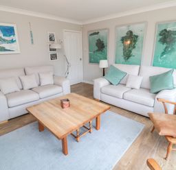 A living room with two beige sofas a wooden coffee table and art on walls at Turnstone in Beadnell
