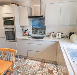 A kitchen with patterned tile floor wooden chairs oven stovetop and countertop appliances at Turnstone in Beadnell