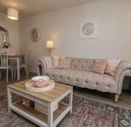 A living room with a sofa and dining area at Seashell Sands in Appledore