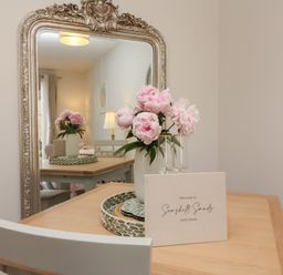 A dining room with a table and flowers at Seashell Sands in Appledore