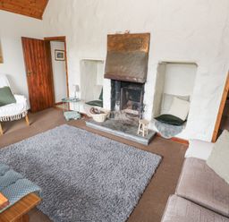 A living room with a fireplace two armchairs a sofa and a gray rug at Bofin in Oughterard County Galway